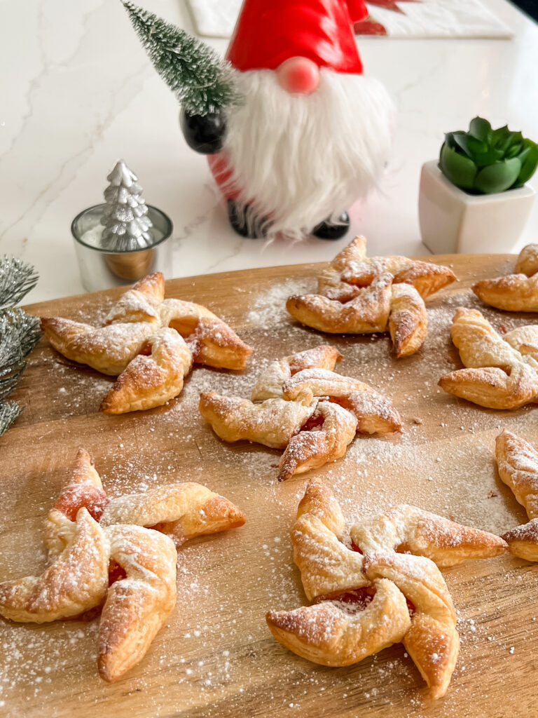 Cooked puff pastry jam stars on a wooden board, sprinkled with icing sugar