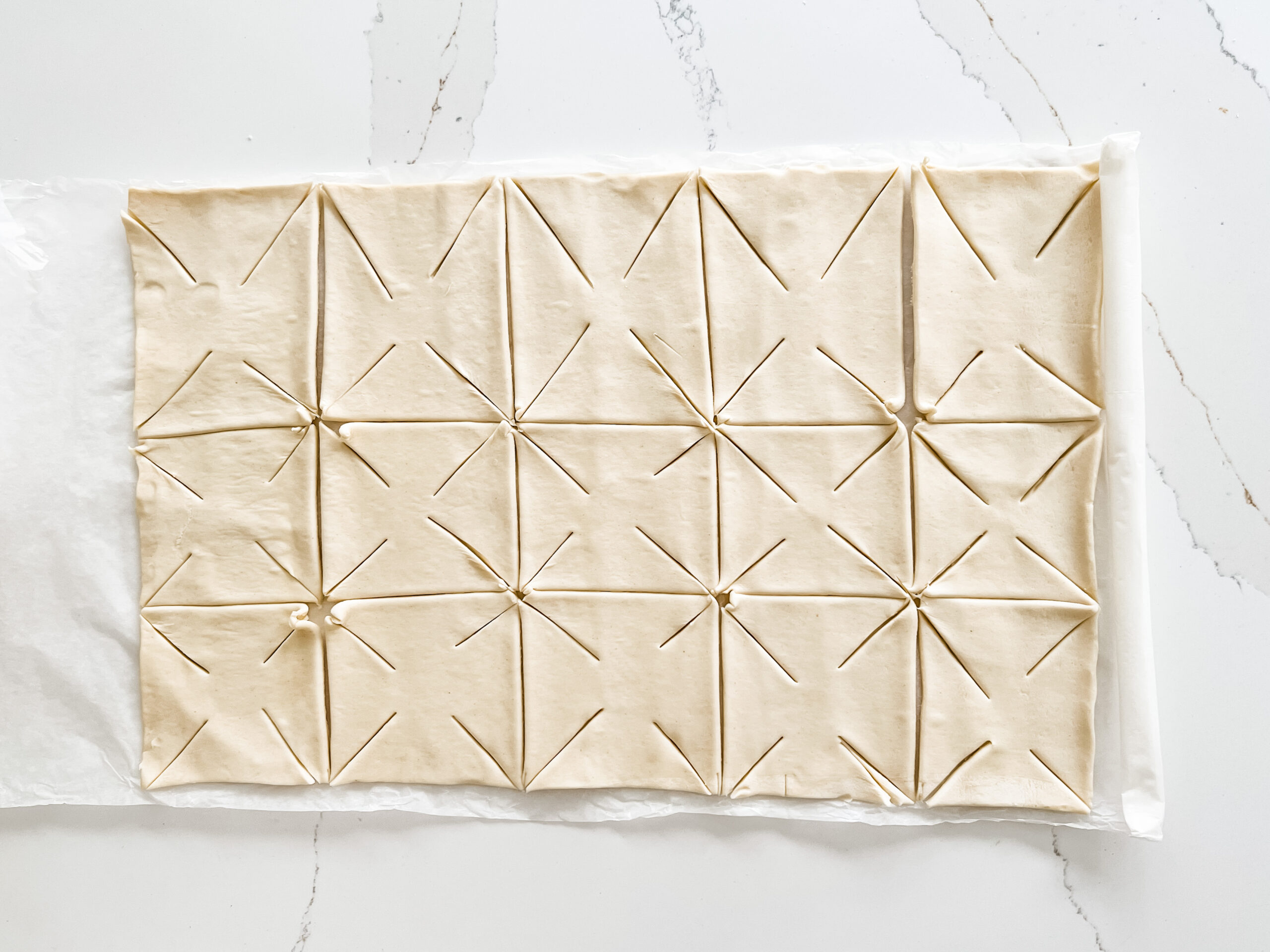A pre-rolled puff pastry sheet cut into squares and then with cuts in the diagonal of each corner