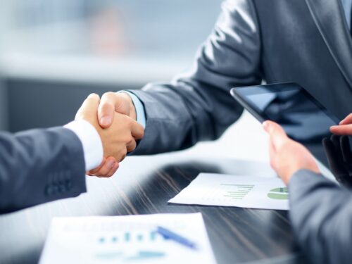 Two business people securing loans by shaking hands over a table.