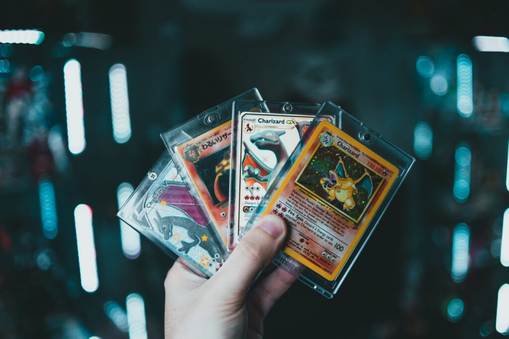 A child holding up several pokemon cards as gift ideas against a dark background.
