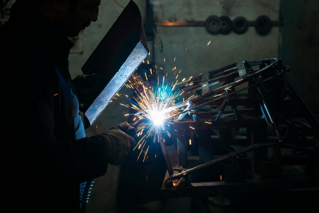 A welder is customizing a piece of metal in a steel workshop.