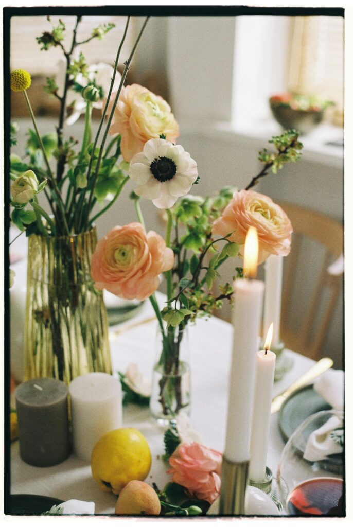 A bedroom table adorned with elegant flowers and flickering candles.