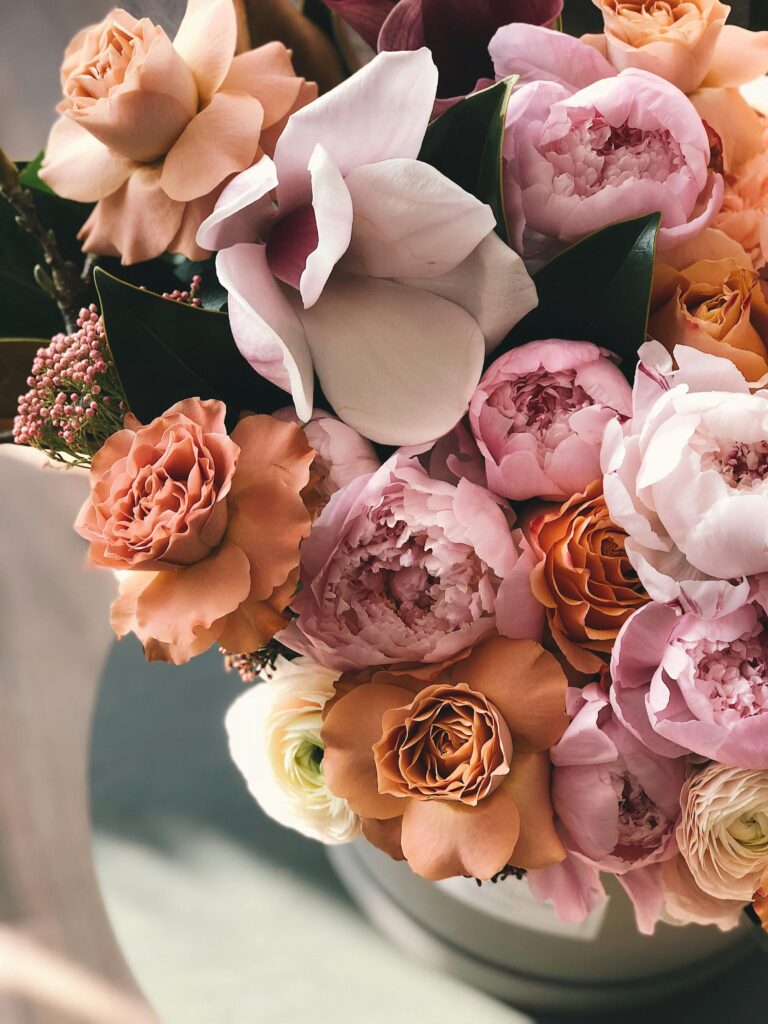 A bouquet of pink and peach flowers on a bedroom table.