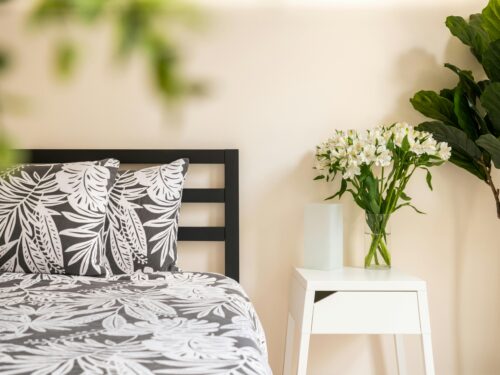 A black and white bedroom with a plant on the side of the bed adorned with flowers.