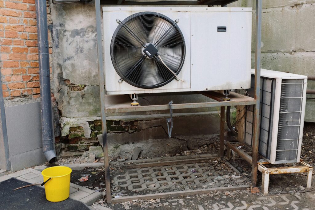 A commercial air conditioning unit with a bucket next to it.
