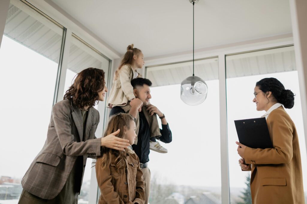 A connected family is standing in front of a window in their new home.