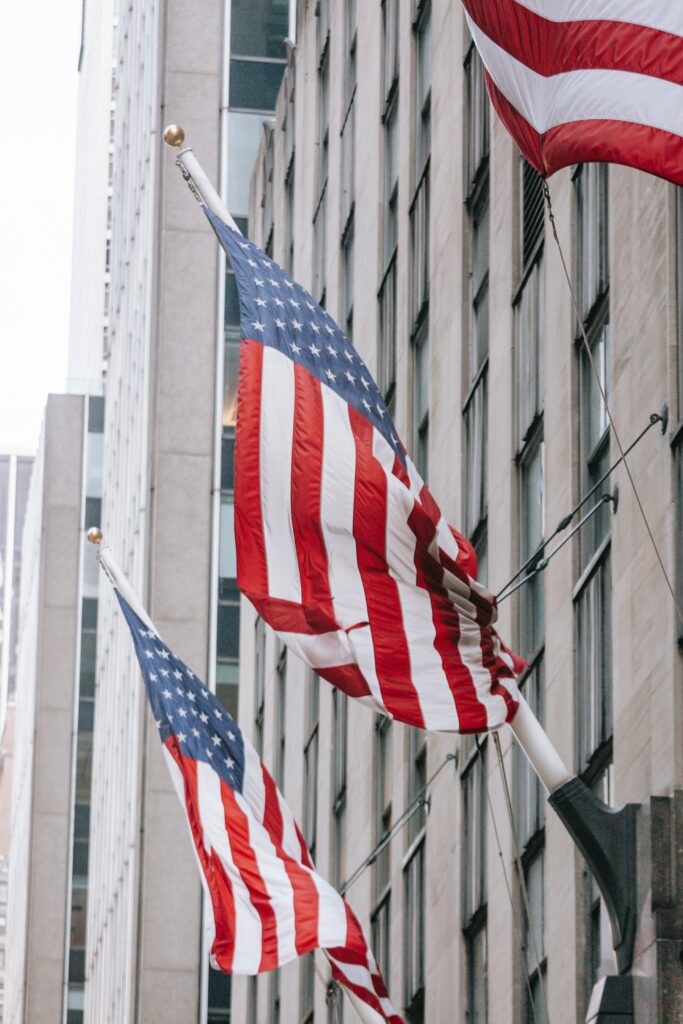 A group of American flags on a pole in front of a building, symbolizing patriotism and national pride.