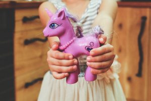 A child holding out a purple my little pony toy