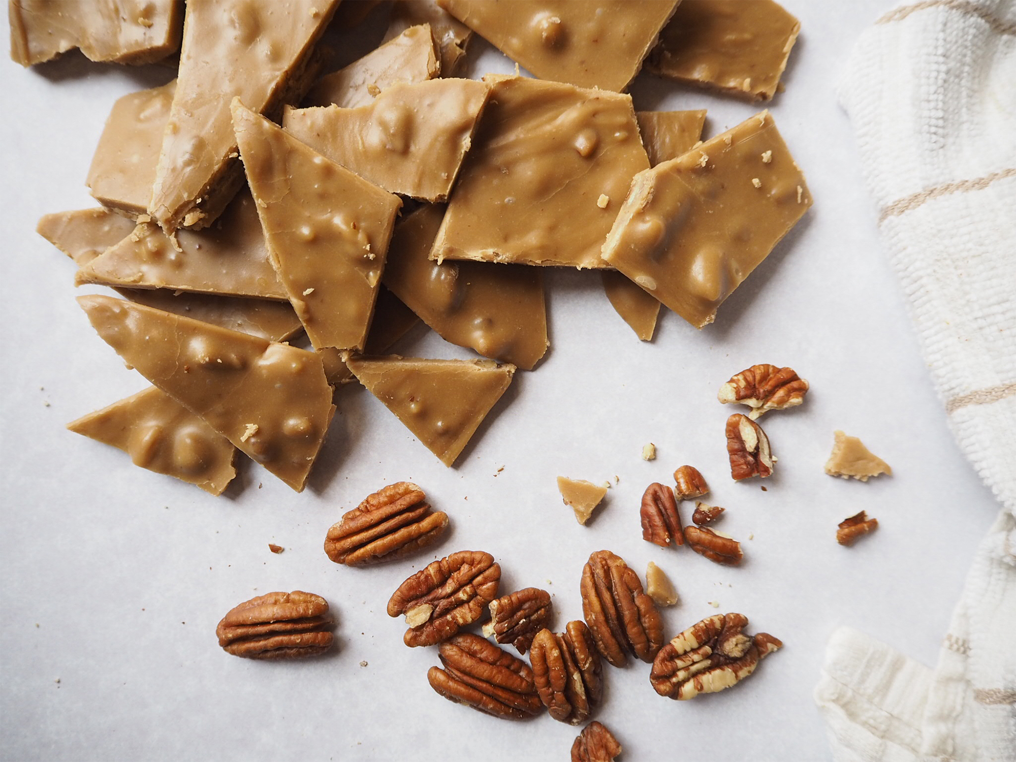 Caramel Frosting pieces in a pile next to some pecans