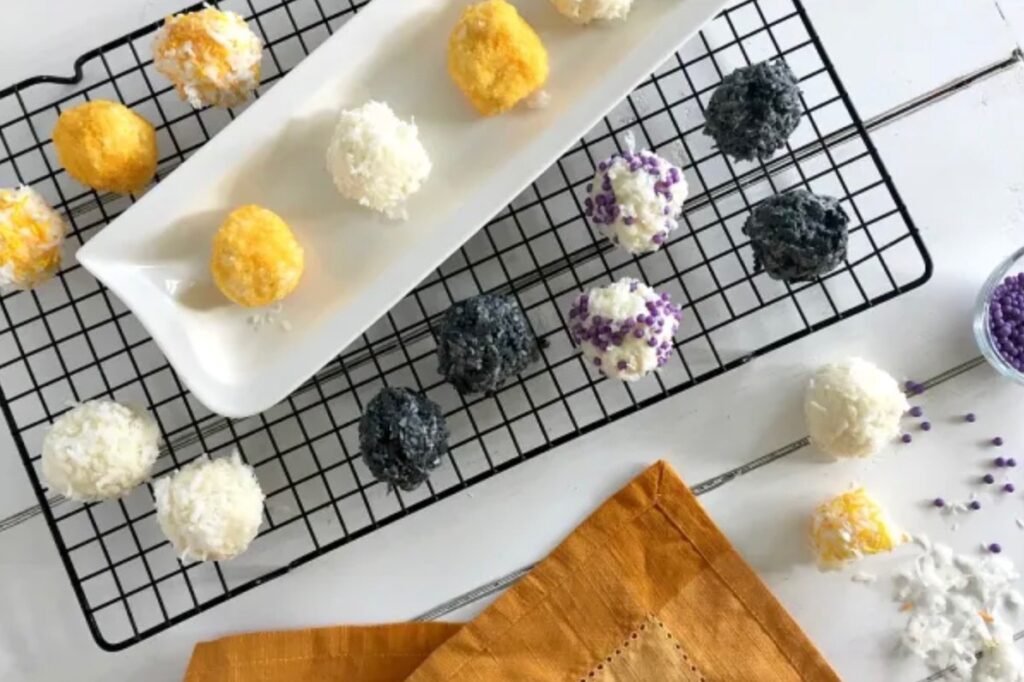 Black, white and yellow coconut snowballs on a white tray and a cooling rack
