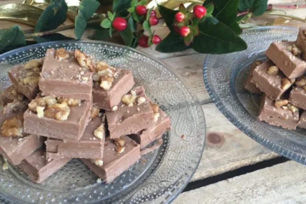 Homemade fudge on a glass dish, topped with walnuts