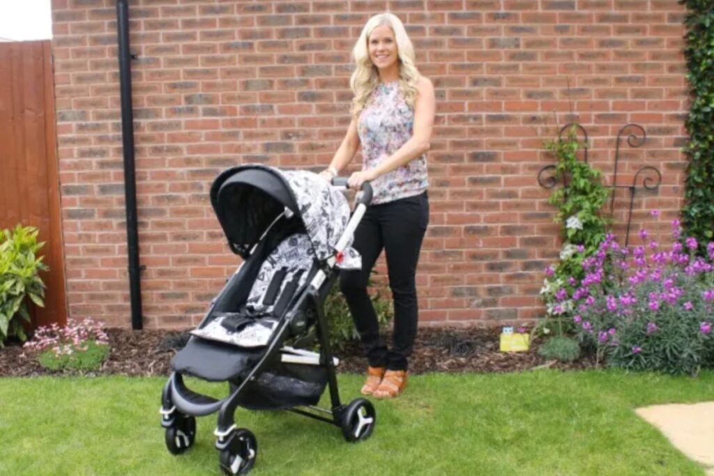 A woman standing in a garden with a black Graco pushchair