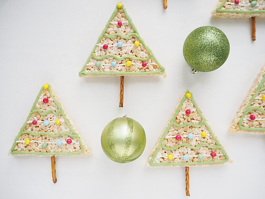 Rice Krispy Treats Christmas Trees with pretzel trunks and 2 large Christmas baubles next to them