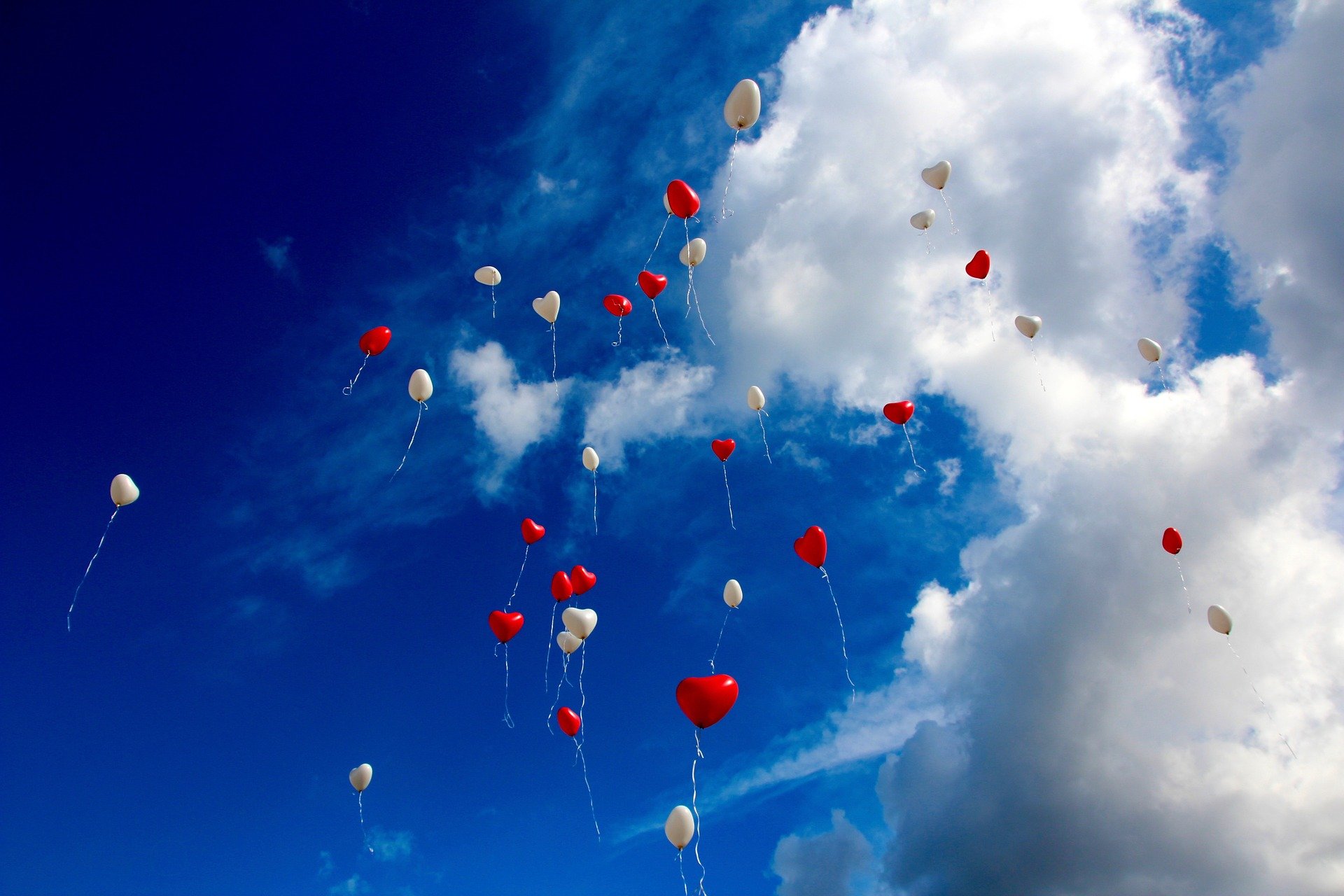 The sky with white and red heart shaped balloons floating away