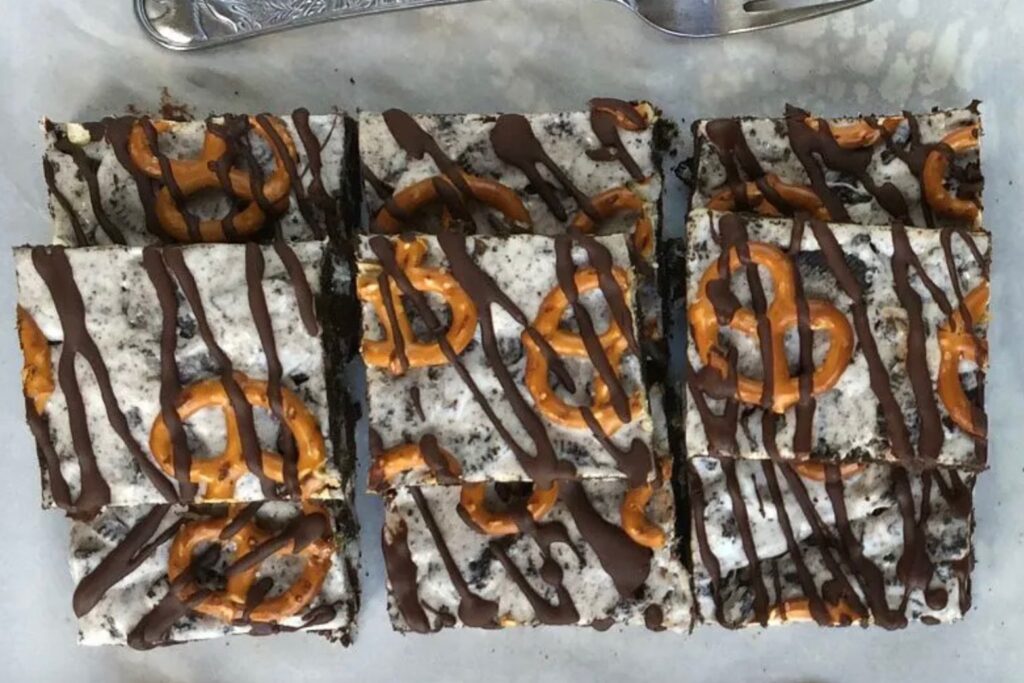 Oreo cookie bars topped with pretzels and stacked on top of each other in a big pile