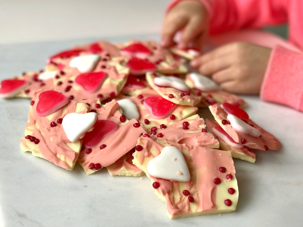 A Valentine's Day treat of chocolate bark. White and pink chocolate covered in pink hearts and sprinkles